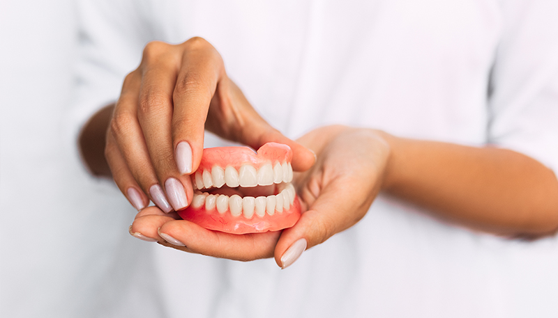 手の平に入れ歯を持ち手を添えている写真
