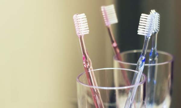 コップに刺さる2本の歯ブラシの写真