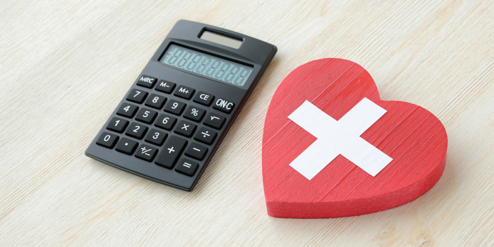 電卓と赤いハートに十字マークの書かれた物の写真