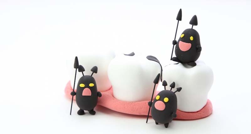 汚れた歯の模型に虫歯菌が集まっているイメージ