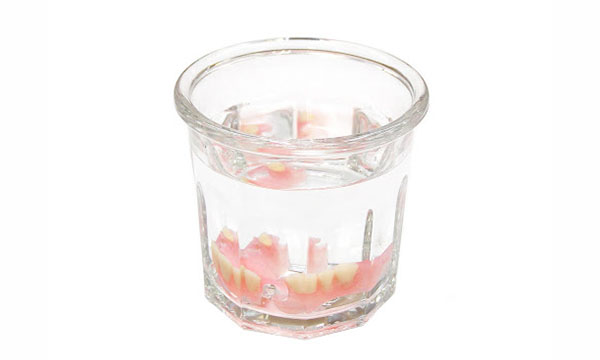 水の入ったコップに沈む入れ歯
