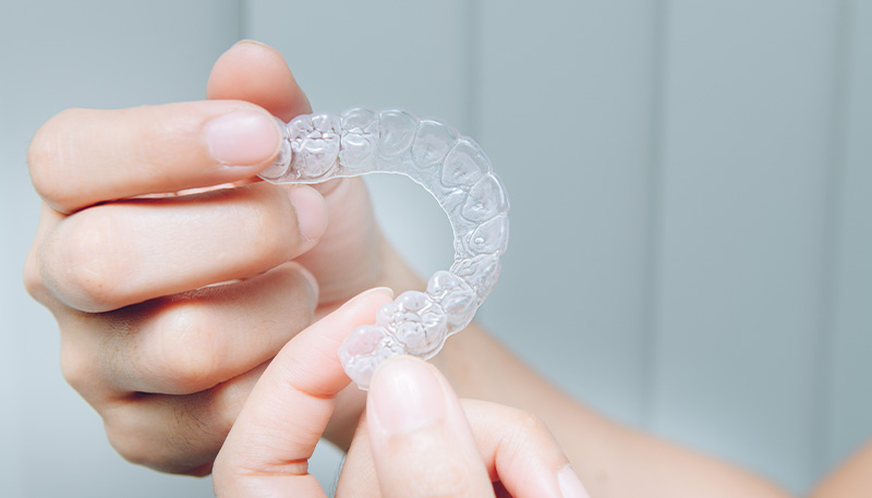 透明なマウスピースを持っている様子