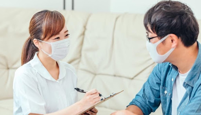 男性の患者さまの問診をとる笑顔の女性スタッフ