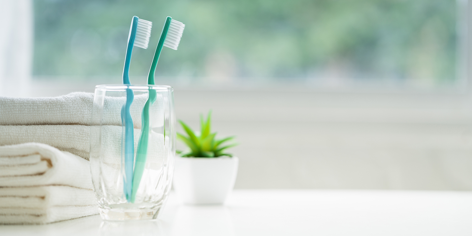 コップに入った歯ブラシ2本とタオルの写真