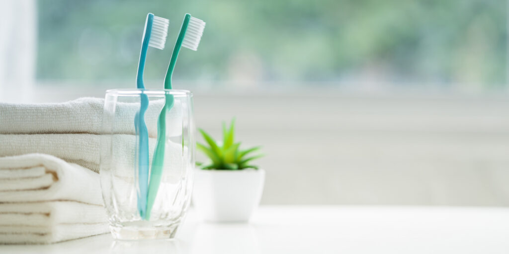 コップに入った歯ブラシ2本とタオルの写真