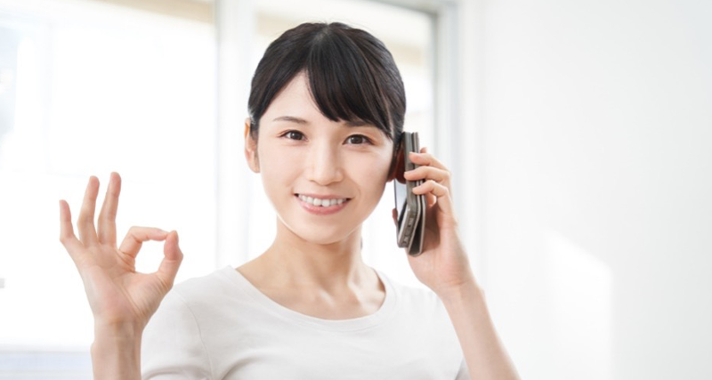 電話をしながら手でOKマークを作る女性